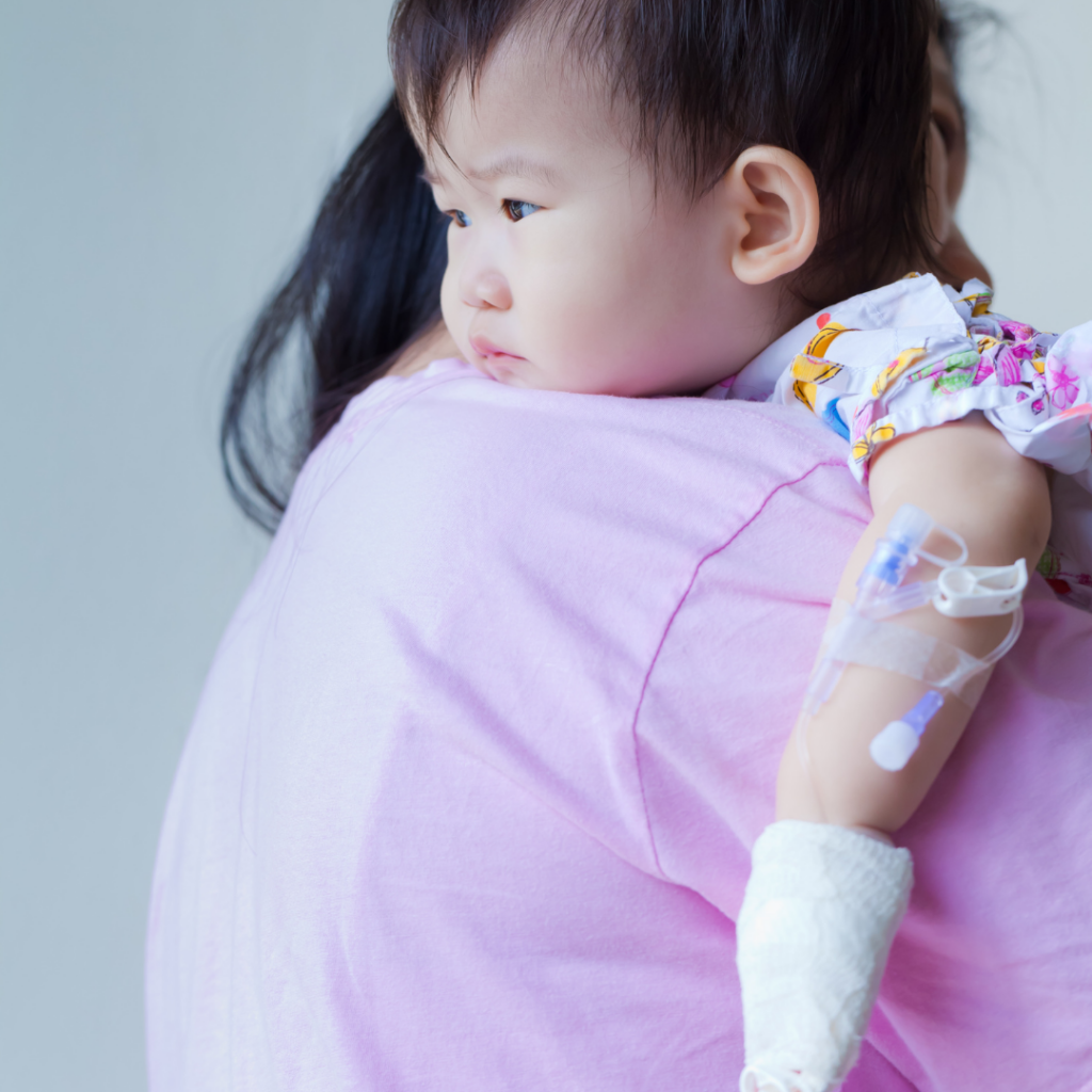 Baby being held by their parent with an IV in their arm.