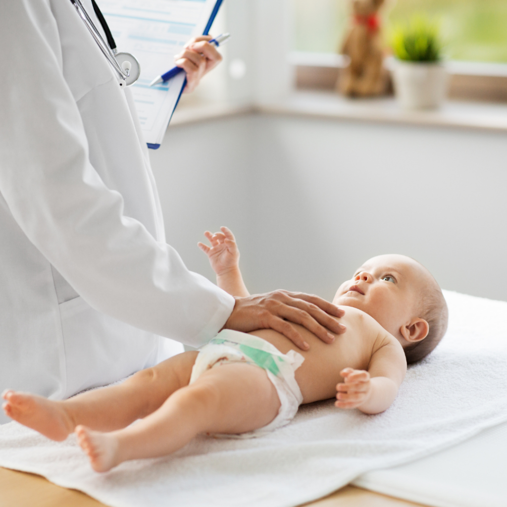 A doctor examines a baby's tummy on the exam table.