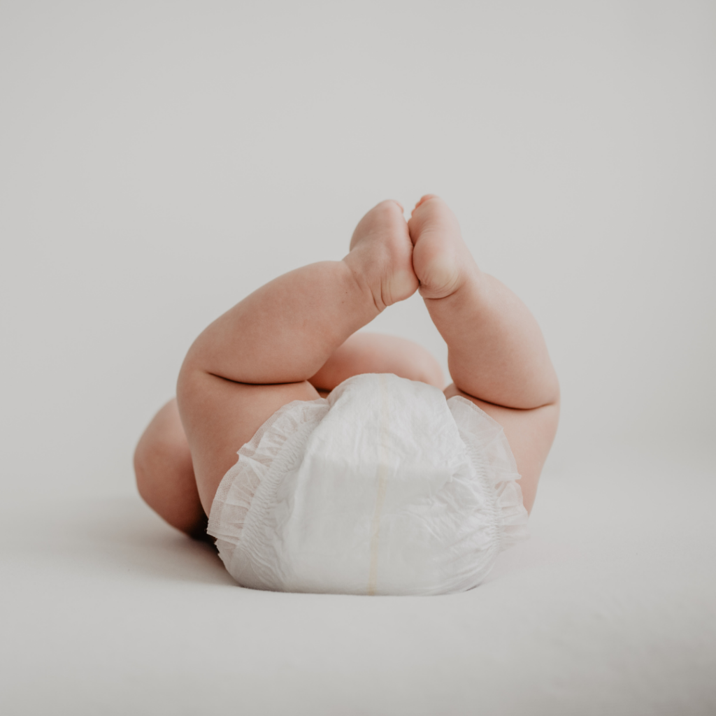 A baby wearing a disposable daper, lying down while waiting for a diaper change or after a change.