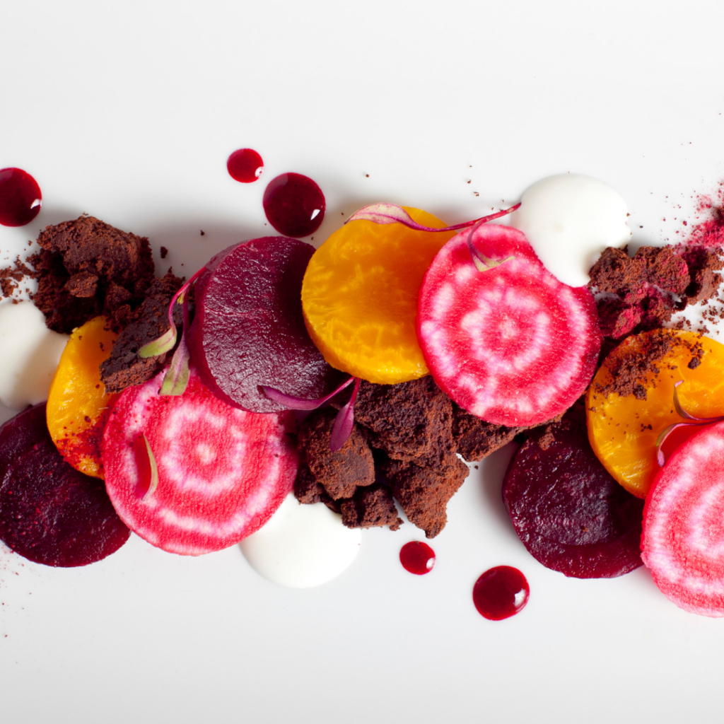 Fresh beets, beet powder, and drops of beet juice piled together in a row, all are natural food coloring options.