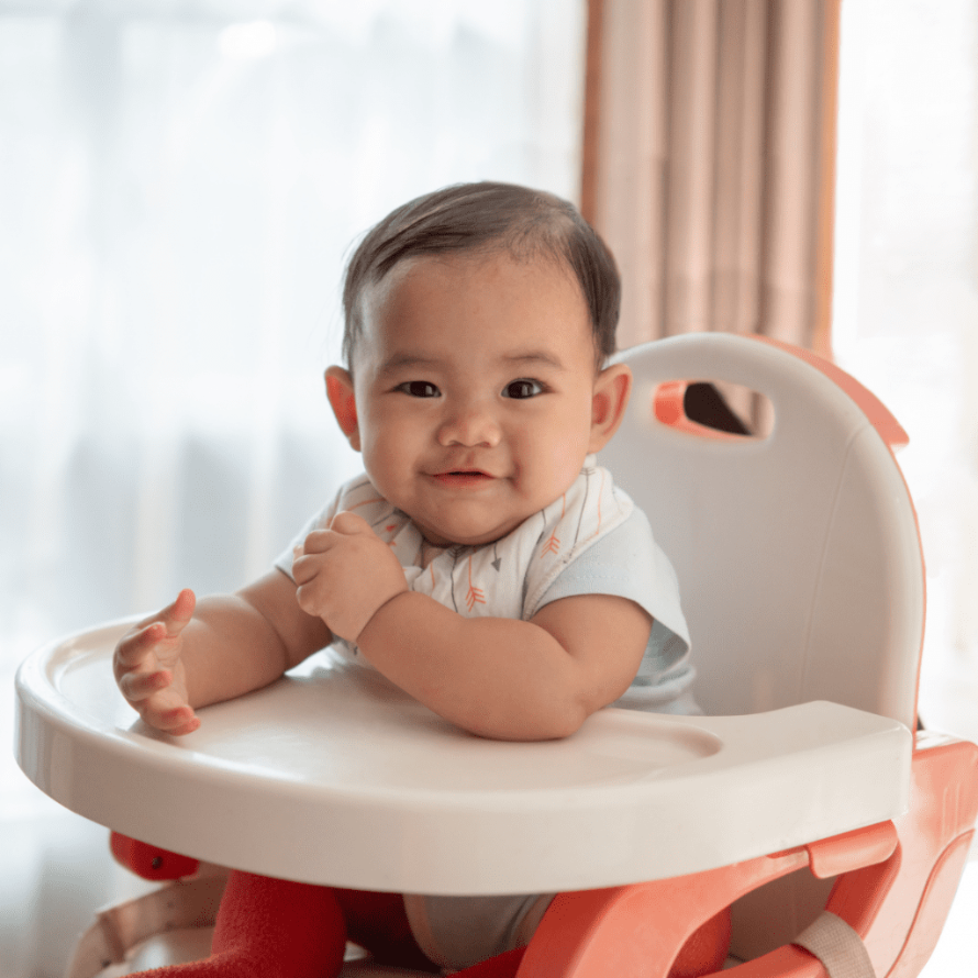 Baby smiling in their high chair while waiting for solid foods.