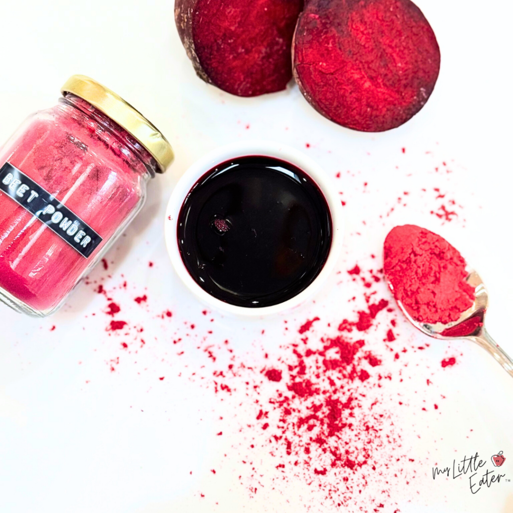 Natural food coloring made from beet powder; dark red liquid in a small bowl with powder in a spoon and jar beside.