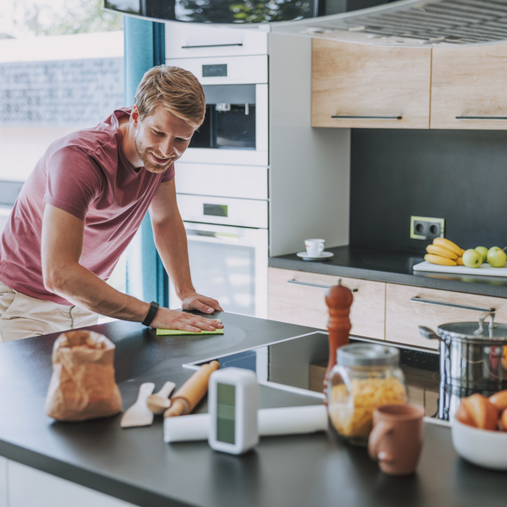 An adult wipes down the kitchen counter after cooking.