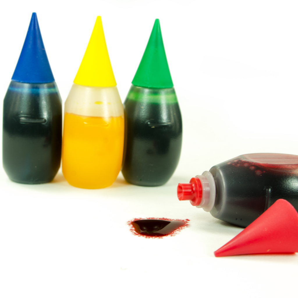 Store bought food coloring with the red bottle tipped over and some spilling out.