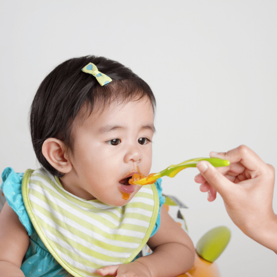 Baby being fed a puree on a spoon as a way to start eating solid foods.