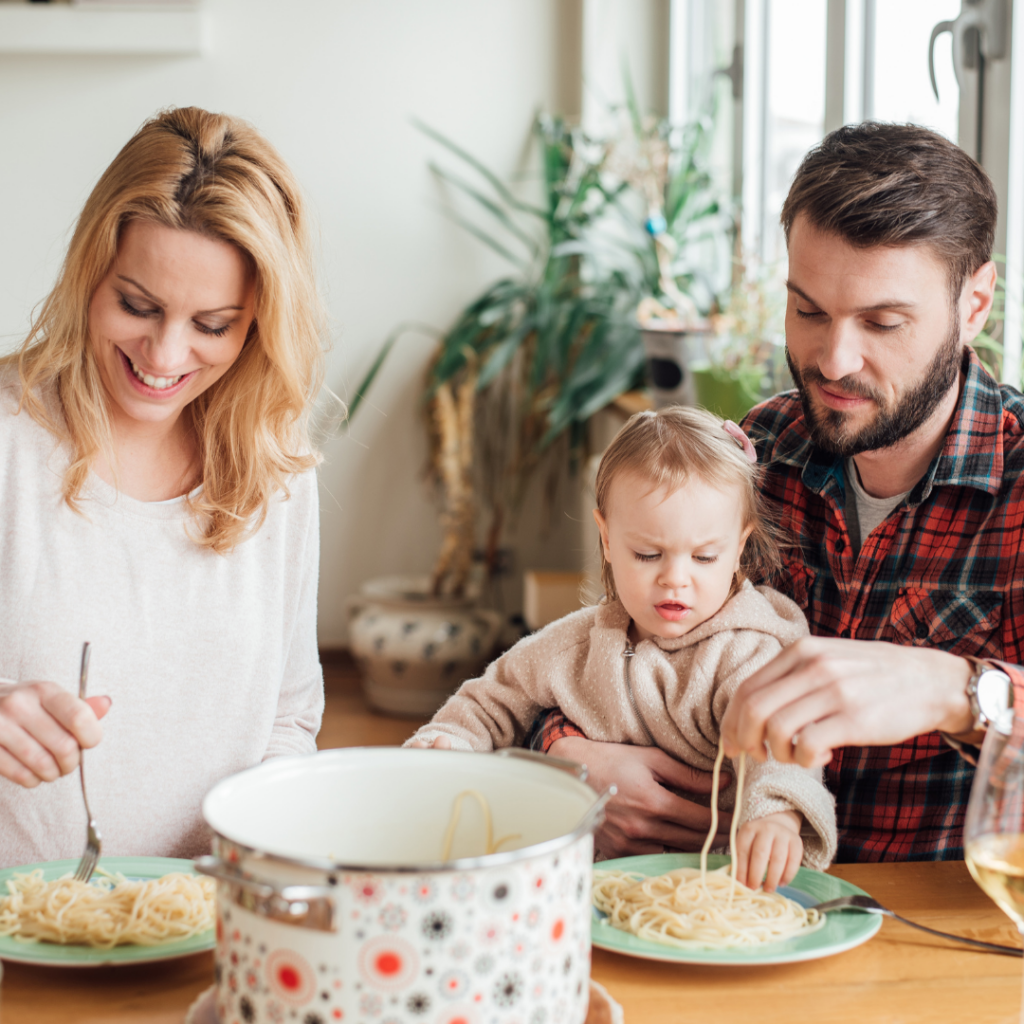 Family sitting together at the table to eat pasta as part of baby's diet.