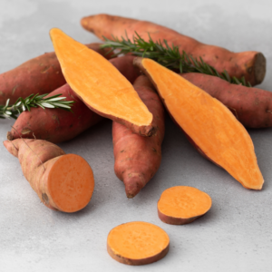 Pile of sweet potatoes, some cut in half and others cut into discs.