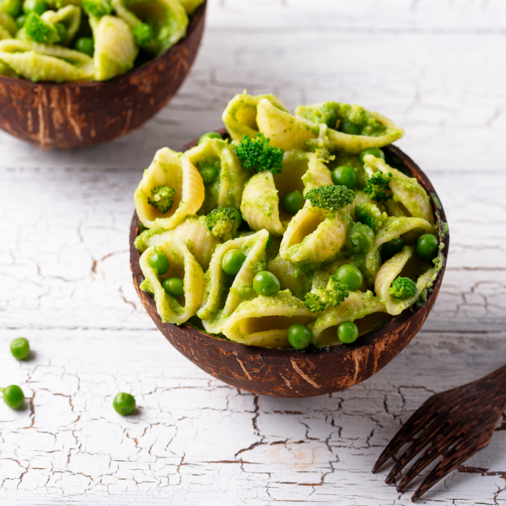 Shell shaped pasta for babies in a bowl mixed with peas.