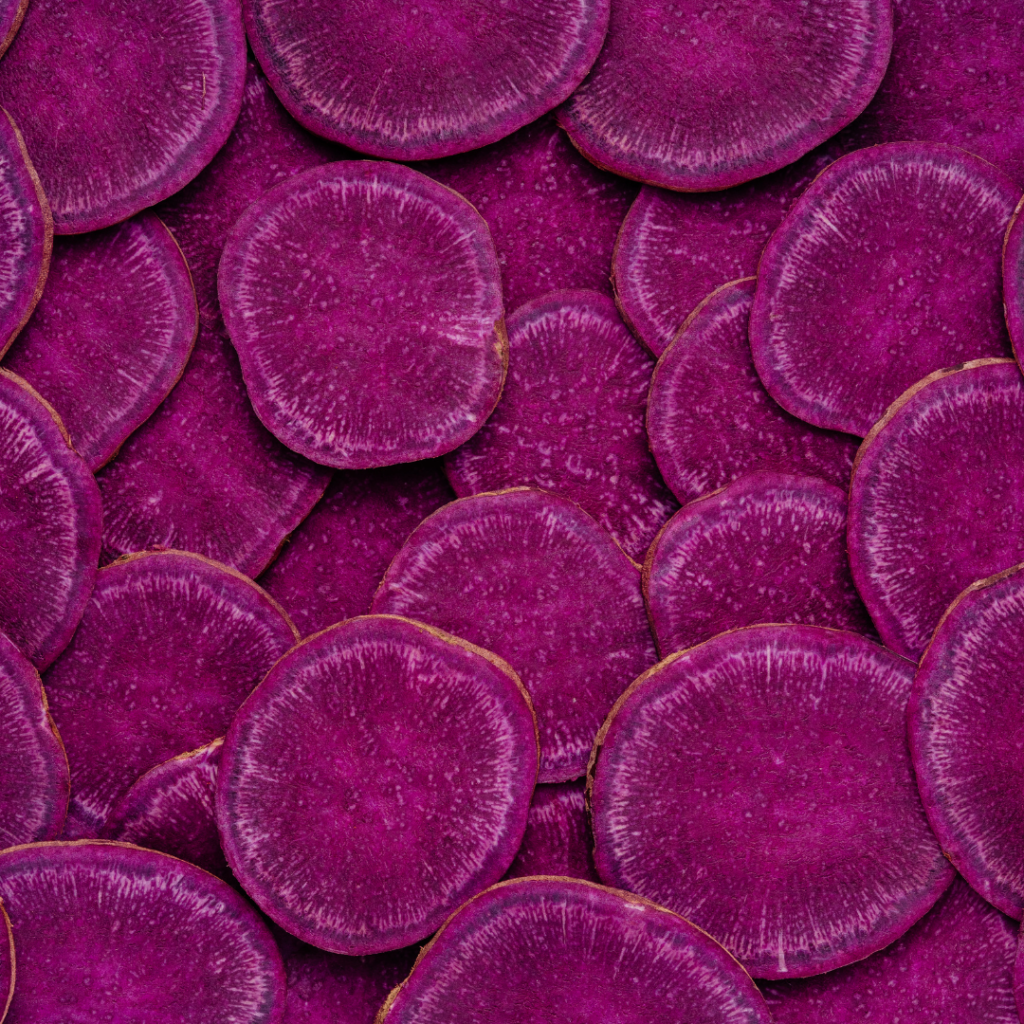 Round, disc-shaped slices of purple sweet potatoes in a pile.