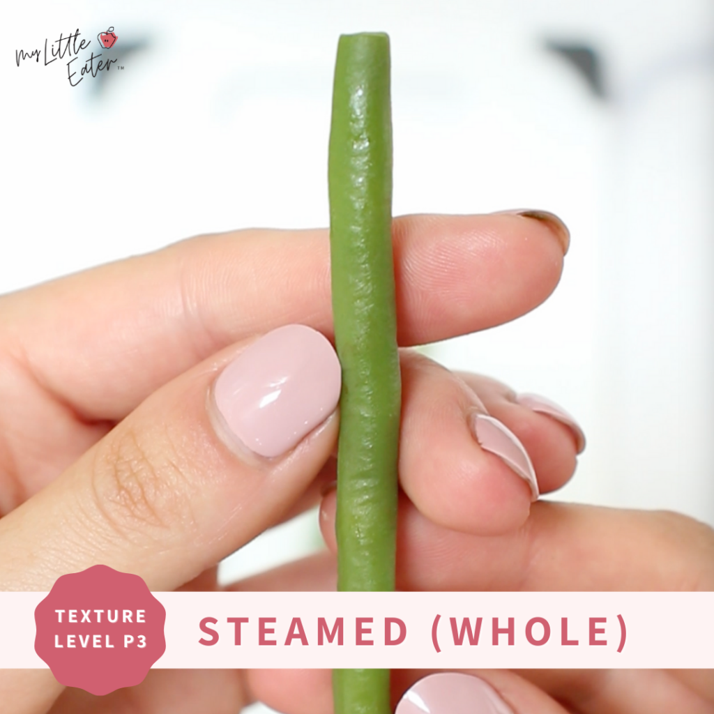 A whole green bean cooked in a steamer basket to make soft to serve as green bean baby food.