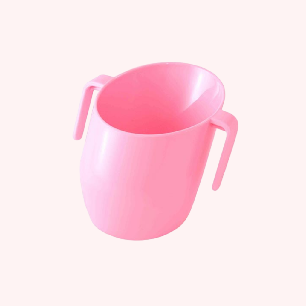 A pink cup for babies with handles and a slanted rim to make it easier for babies.