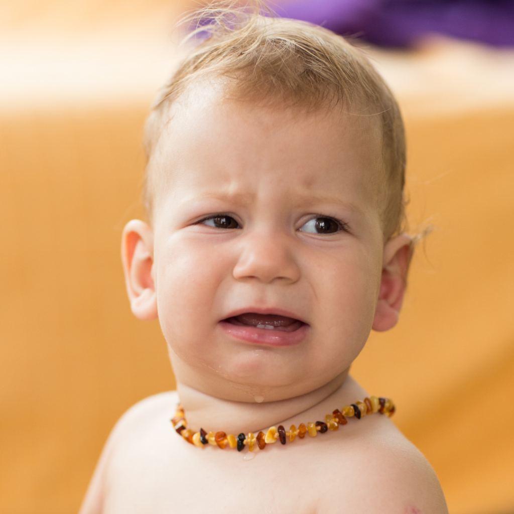 Baby appears upset while wearing one of the many available options of amber teething necklaces which are deemed a choking hazard.