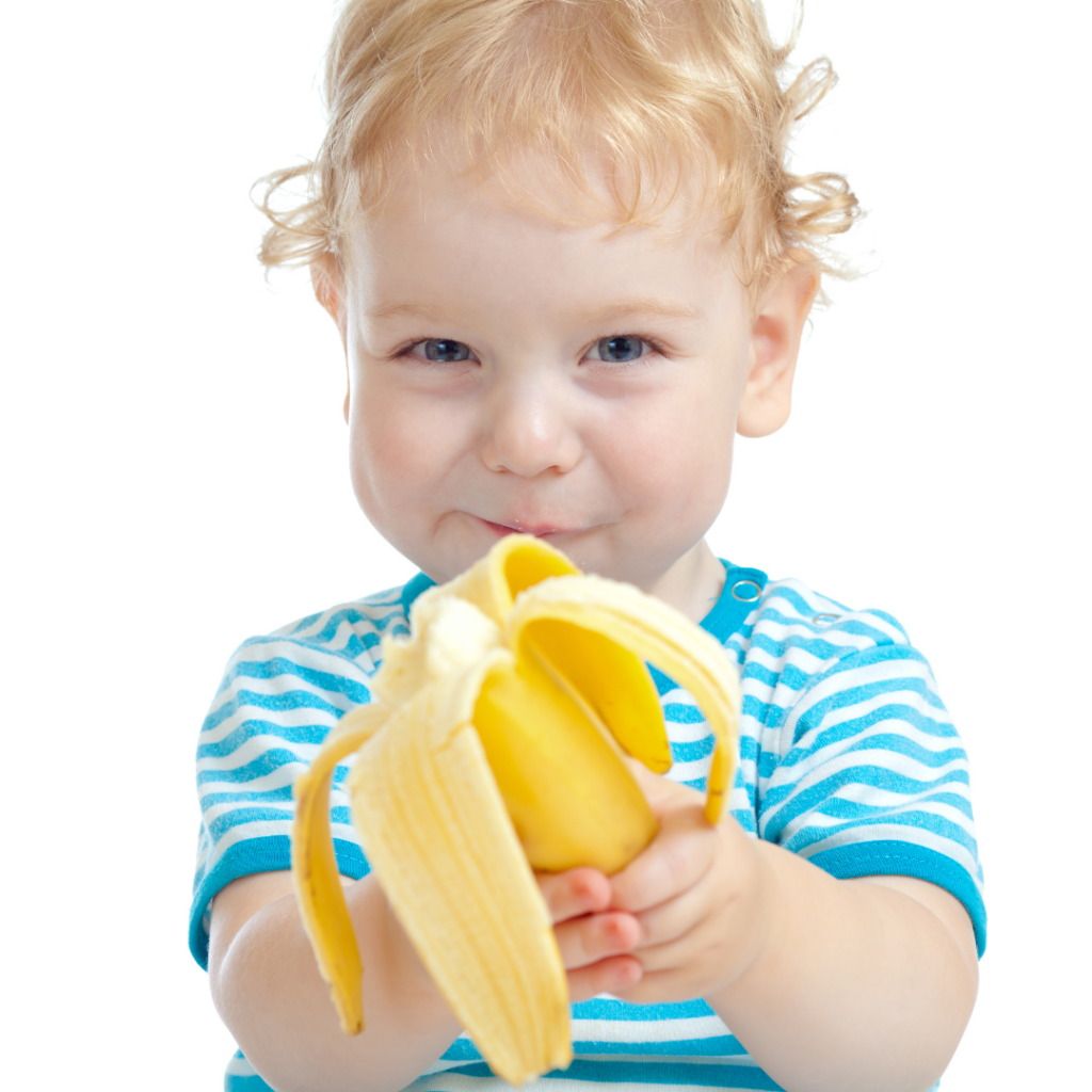 Baby learning to eat soft finger foods is holding a banana still in its peel.