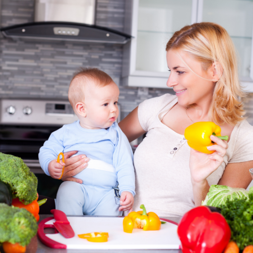 A baby watches their mom cut peppers.