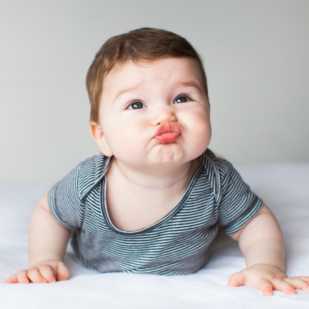 Baby doing tummy time with their lips pushed into a "kiss" face.