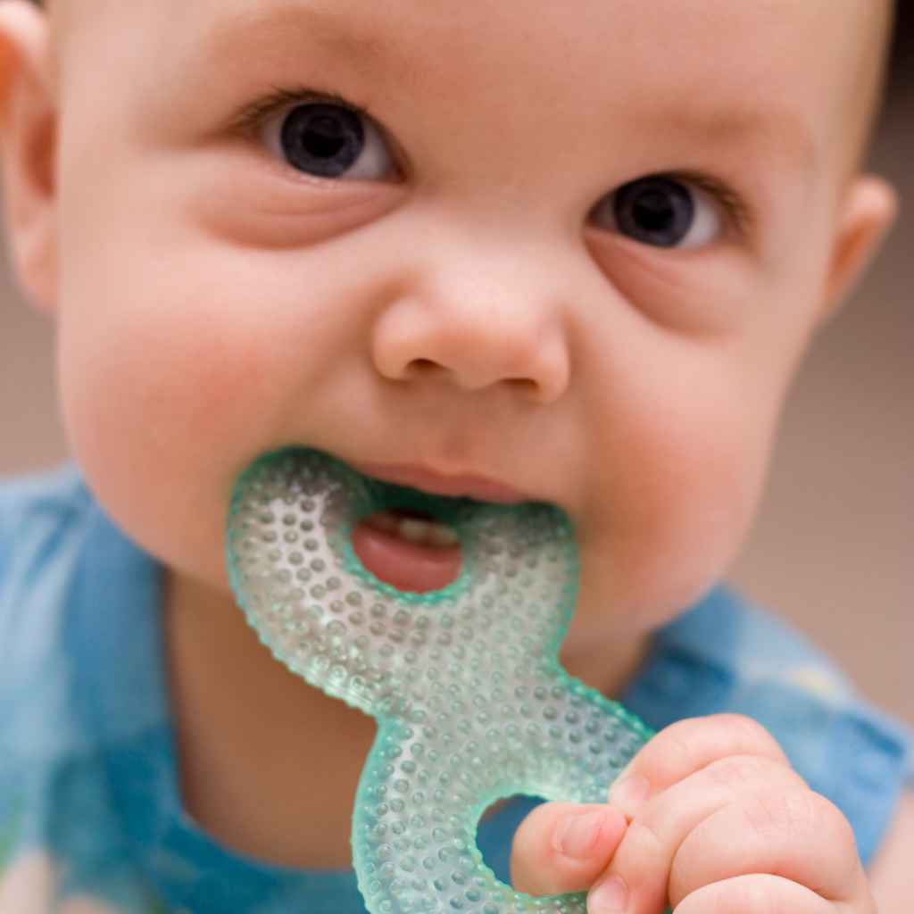 A close-up of a baby chewing on a teething ring.