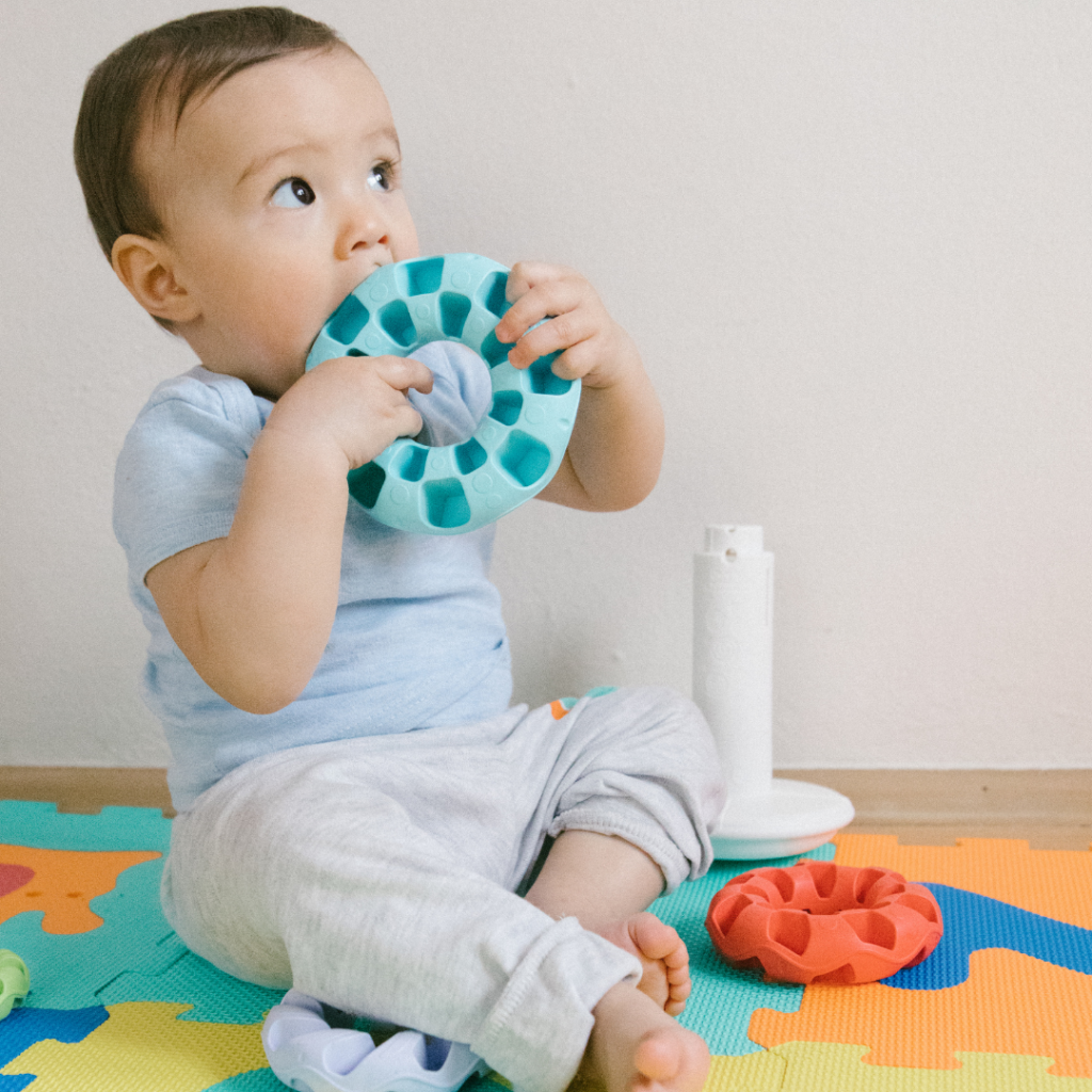 Baby sitting and practice chewing on teething toys.