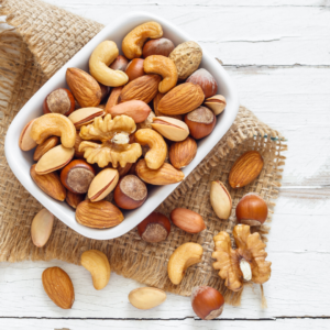 Bowl filled with various whole nuts including almonds, walnuts, cashews, and other nuts.