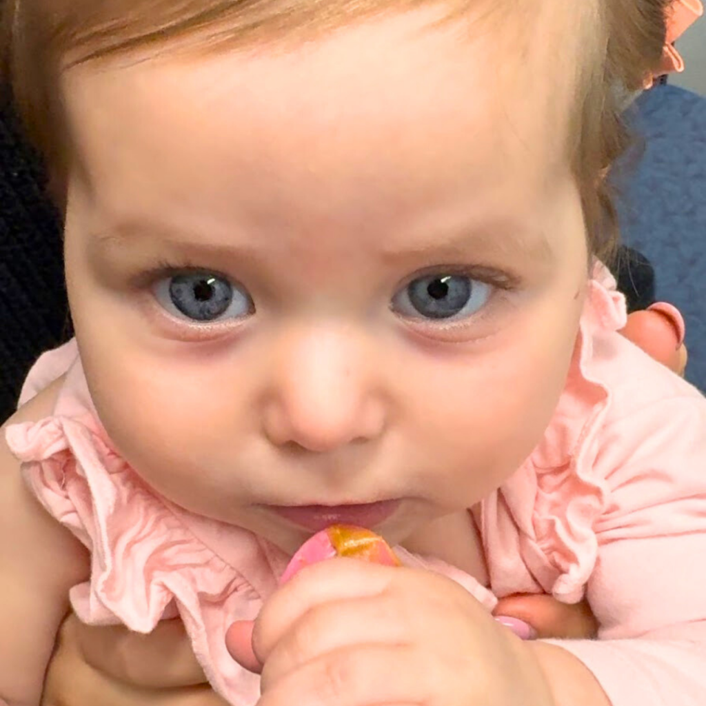 Close-up image of a baby holding a spoon of nut butter.