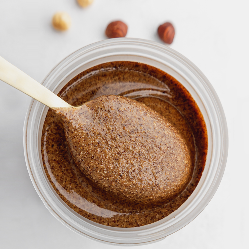 Jar of nut butter for introducing nuts to babies with some being scooped out of the top.