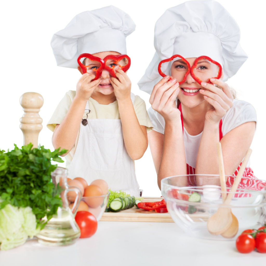 Child and parent have fun in the kitchen while cutting peppers and holding them up to their eyes like glasses.