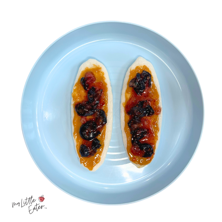 Smooth peanut butter and jam on a rice rusk, plated on a blue toddler plate.