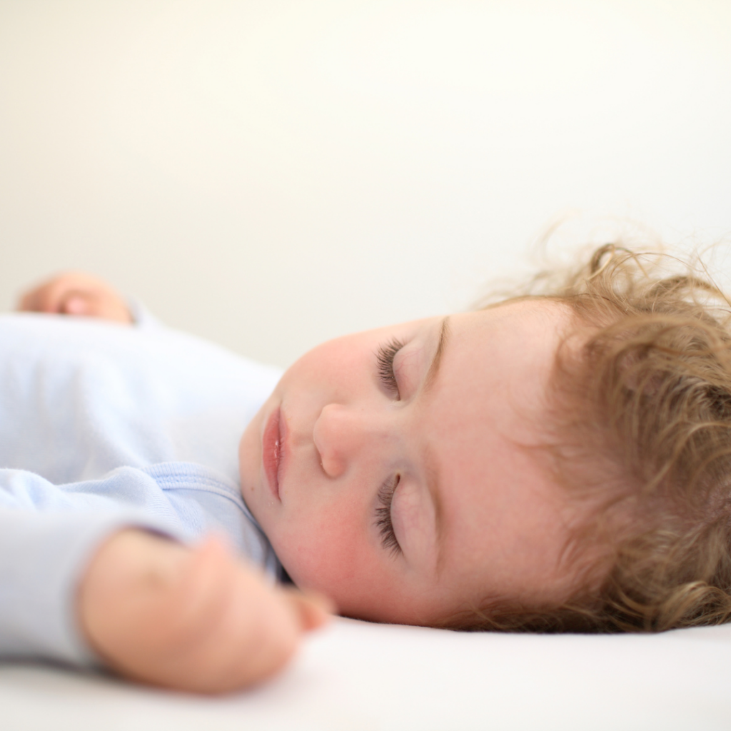 A baby sick with a stomach bug or sore throat sleeps in their crib.