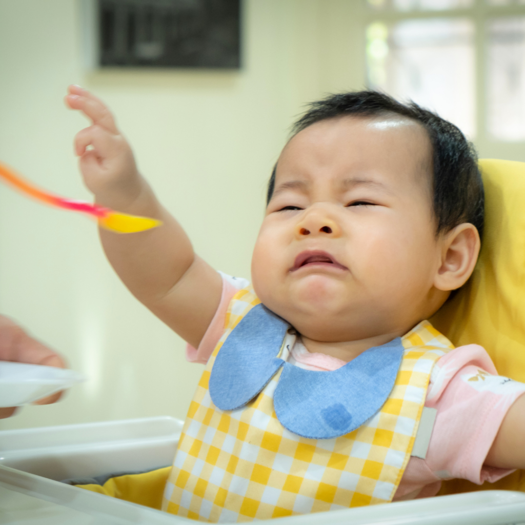 Sick children often refuse food, this baby is pushing away the spoon when parent tries to help their child eat.