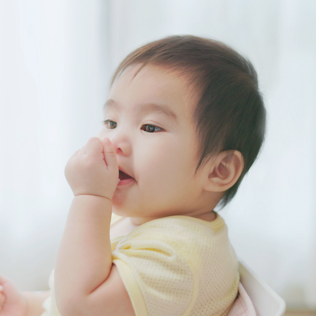 A baby using their palmar grasp to bring something to their mouth.