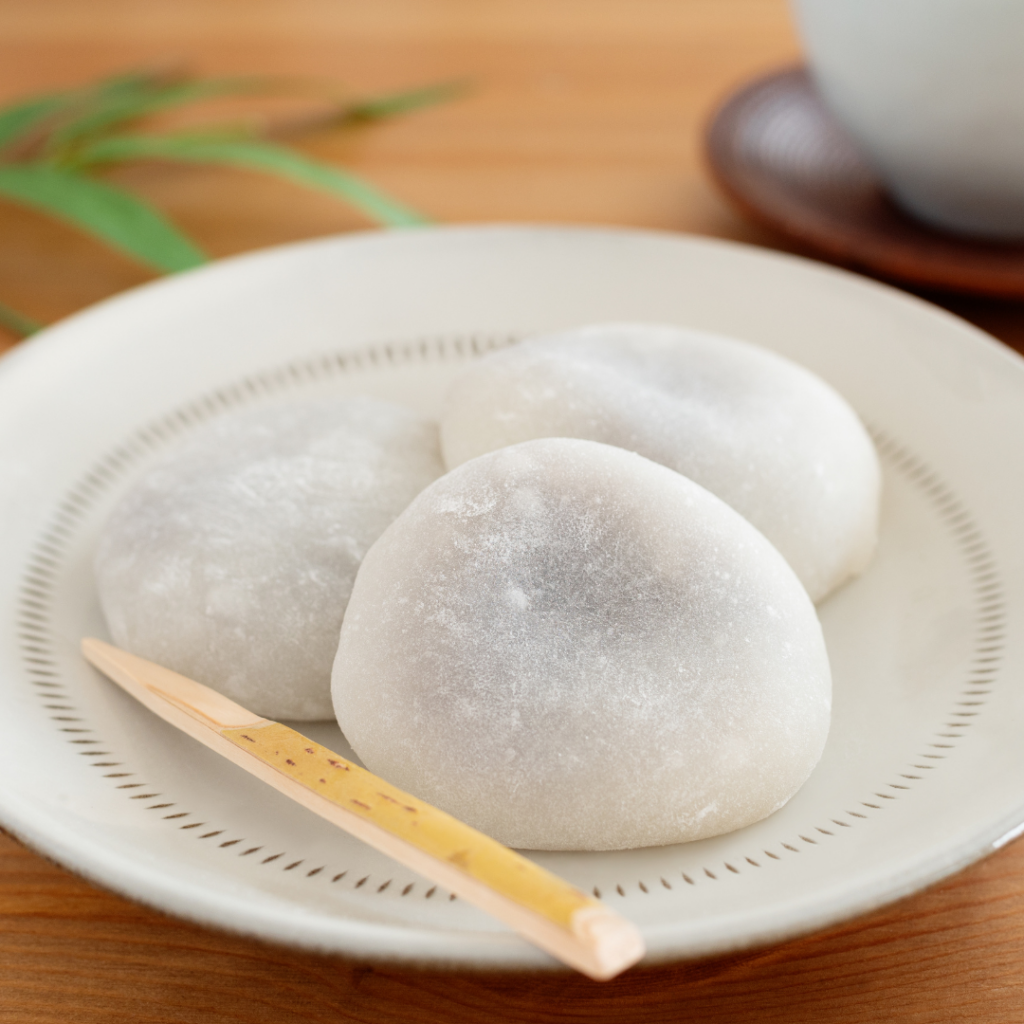 A plate with 3 white mochi on it.