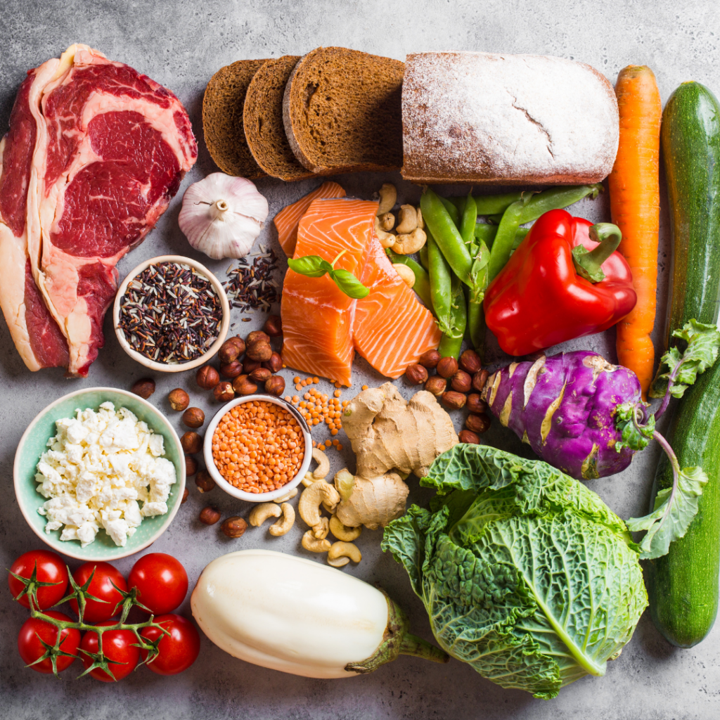 An image of various healthy foods including raw steak, tomatoes, salmon, carrot, pepper, ginger, etc