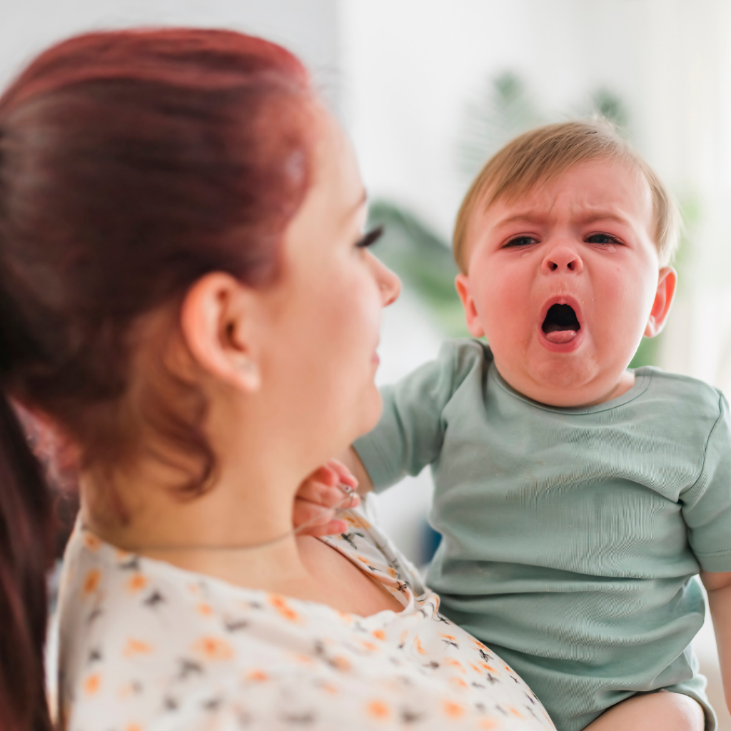 A mother holds her baby who is gagging on solid foods.