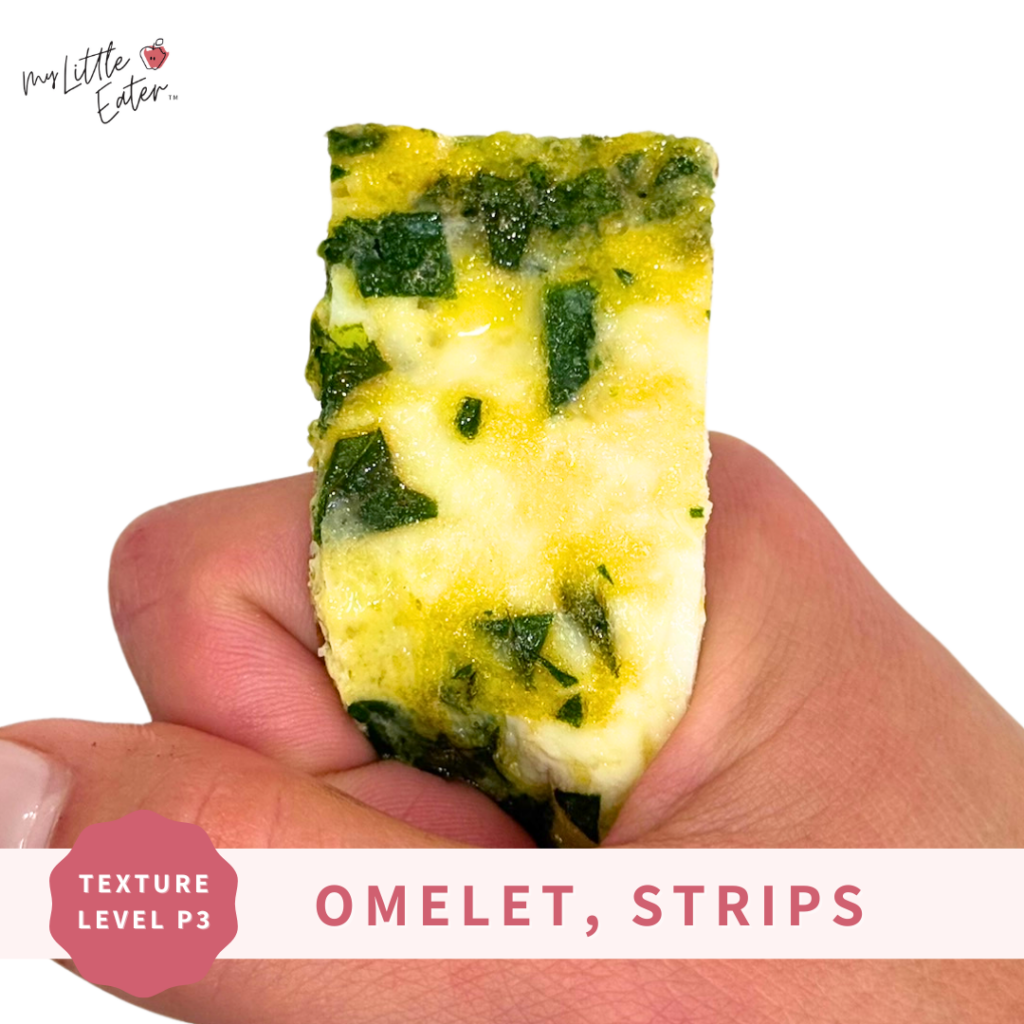 A baby omelet with spinach cut into a strip being held in a palmar grasp for baby led weaning.