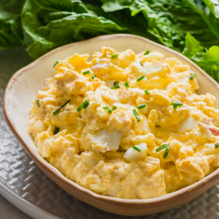 Bowl of well-cooked egg (hard boiled eggs) in bite-sized pieces mixed with mayo and spices to make an egg salad for baby led weaning.