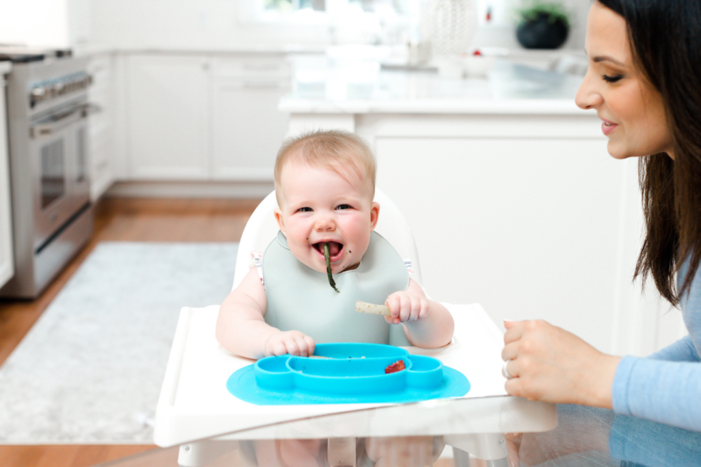 Baby eating green bean while monitored by a pediatric dietitian.