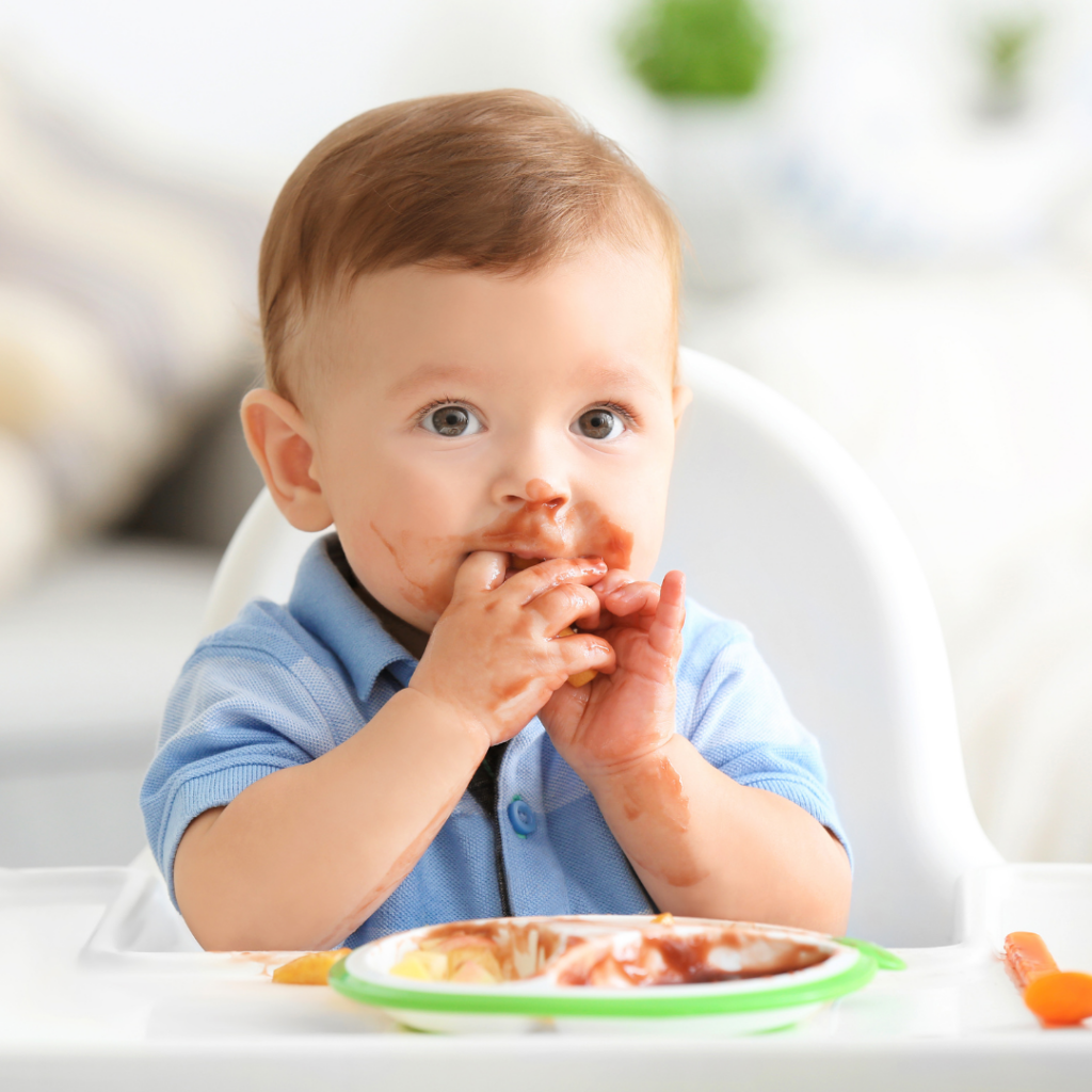 An infant eating finger foods while sitting in their high chair.