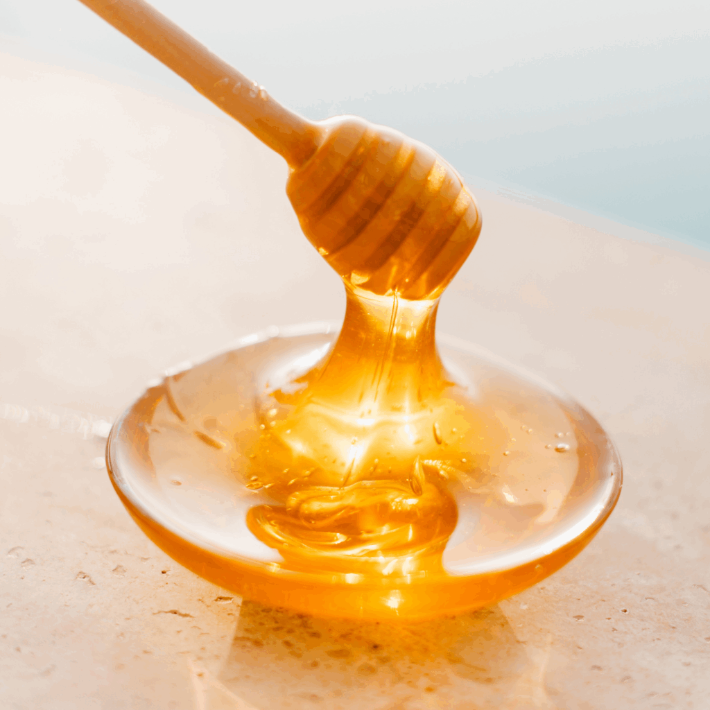 Honey dipper making a splash of raw honey.