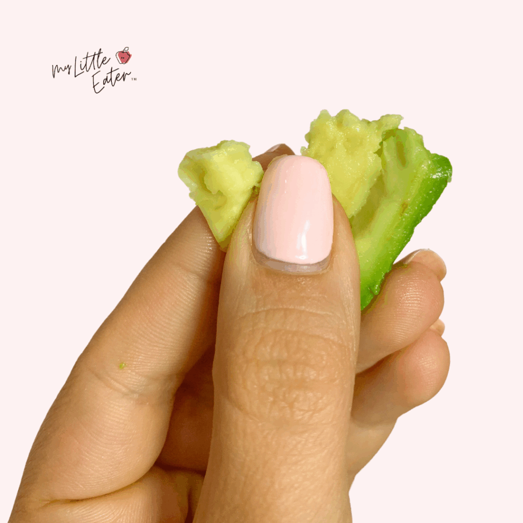 Hand demonstrating the squish test with a piece of avocado.