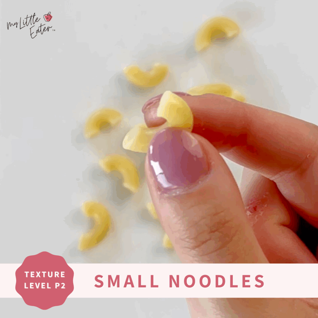 Small macaroni being held between a thumb and forefinger.