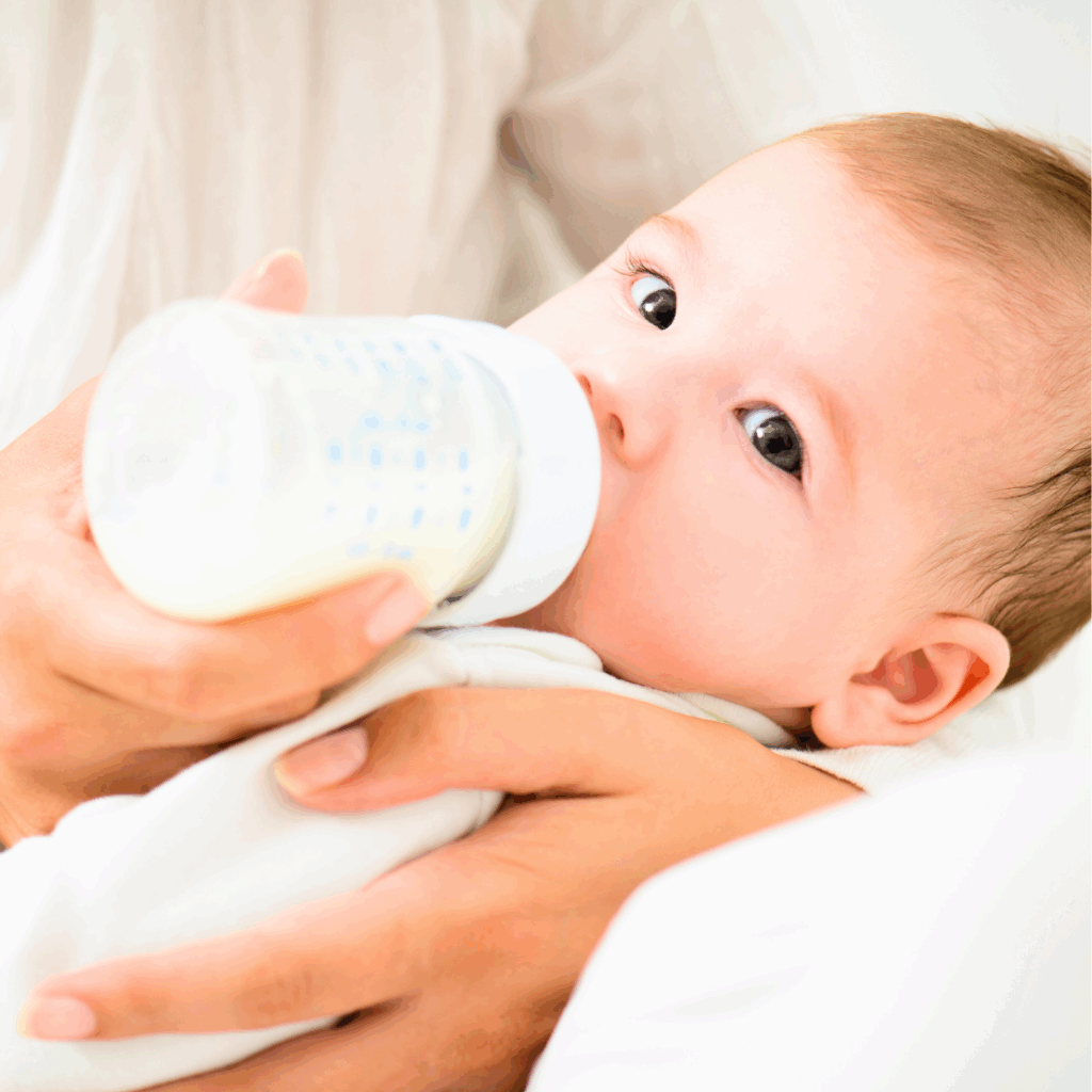 A baby rests in his mother's arms while she bottle feeds him