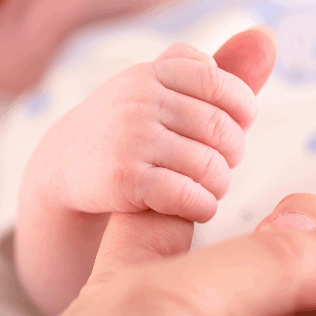 A baby grasps their parent's thumb using their palmar grasp