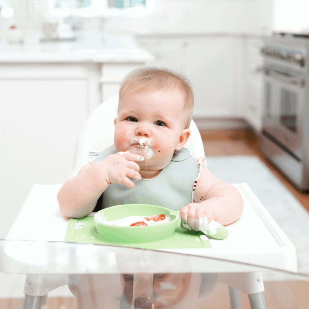 Baby exploring yogurt in the high chair