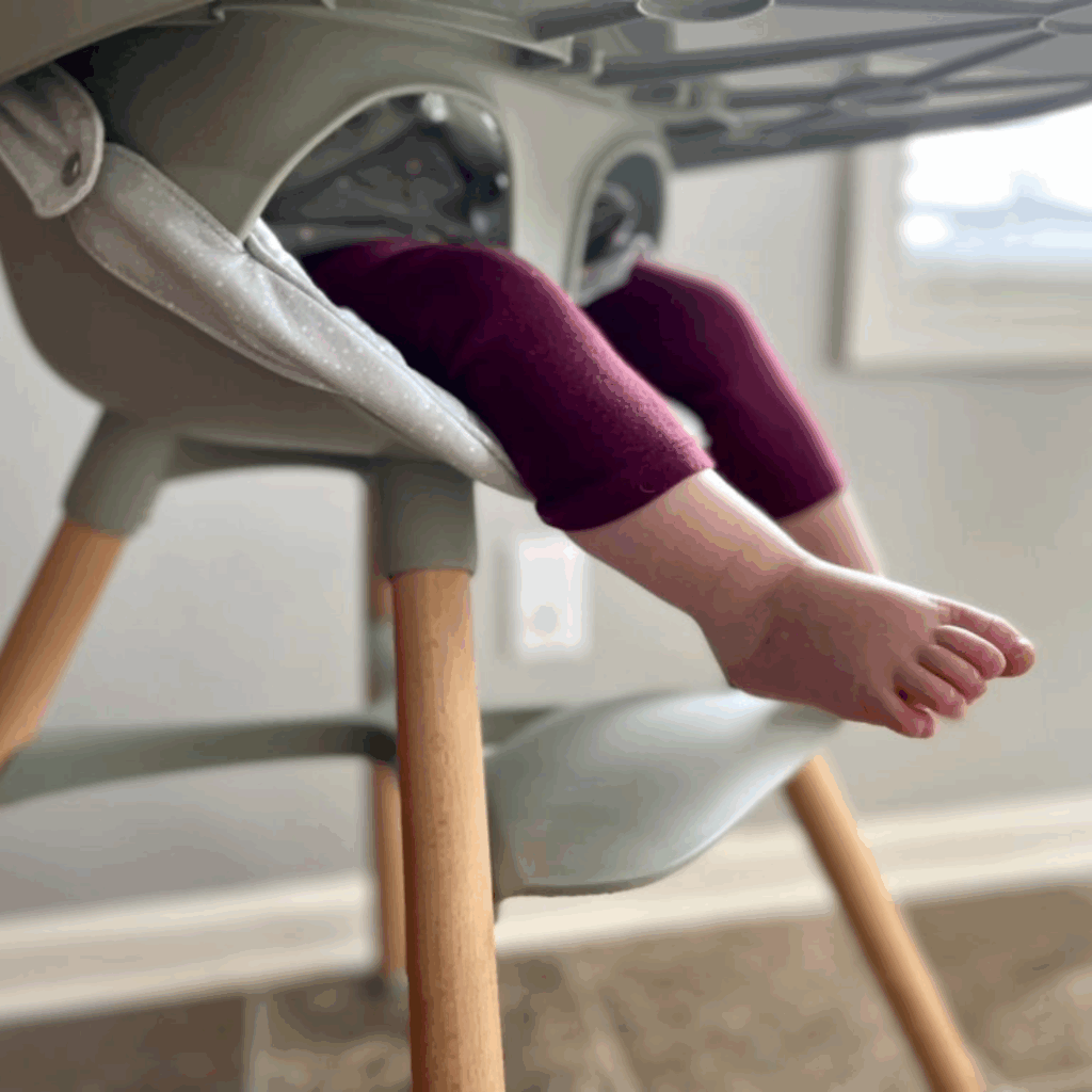 Babies' feet aren not touching the foot rest of the high chair
