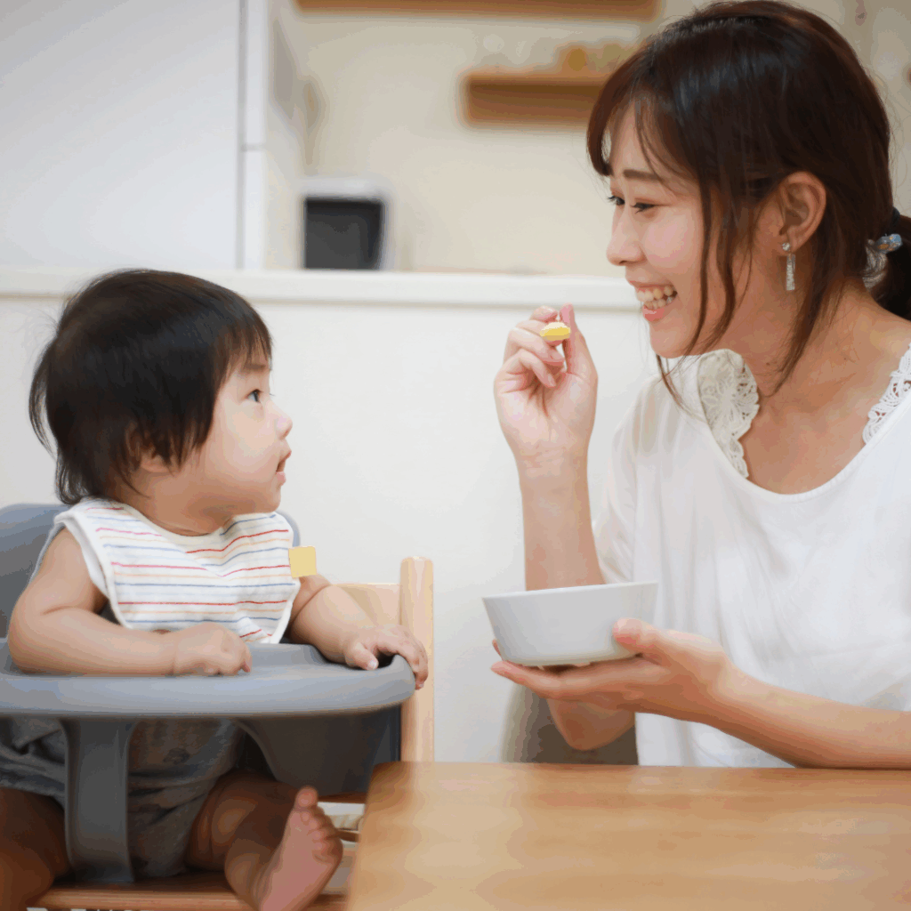 A mom serving the solids to a baby on a spoon.