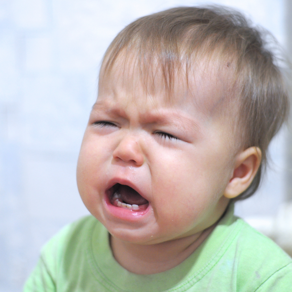 Baby with a green shirt crying. 