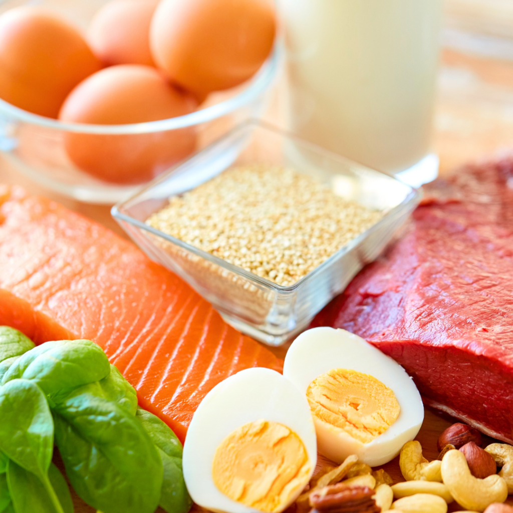A closeup image of high iron foods including salmon, eggs, red meat, spinach, seeds.