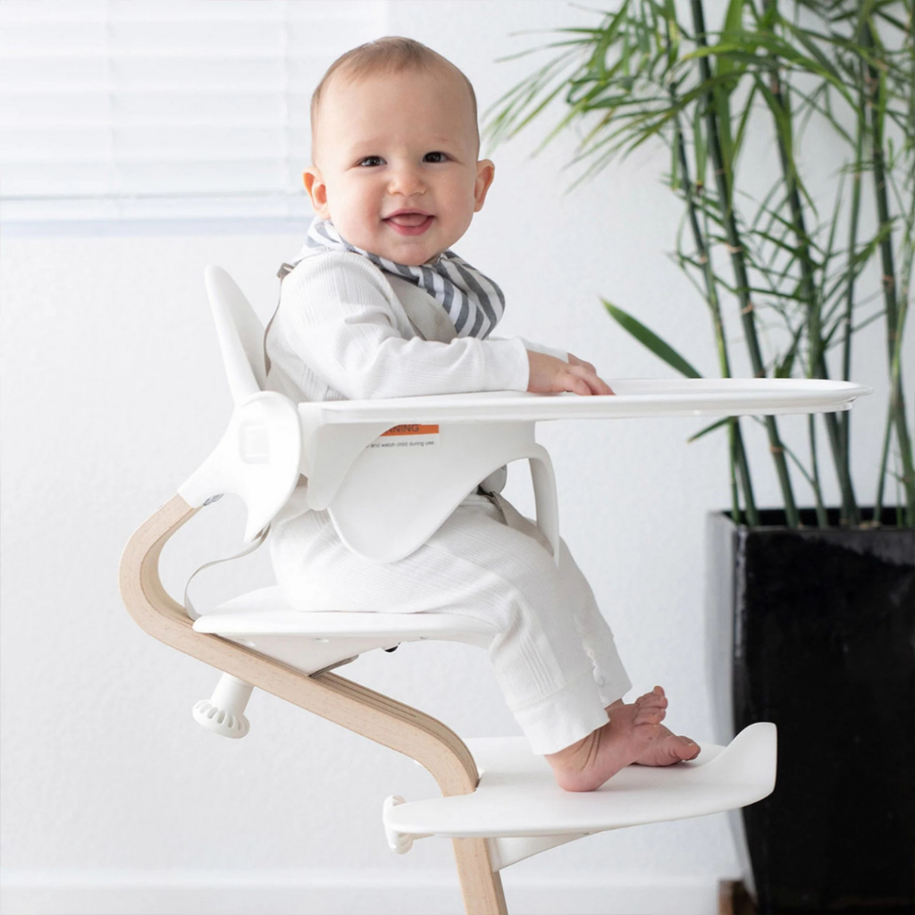 Baby sitting upright in a nomi high chair, showing all developmental signs of readiness.